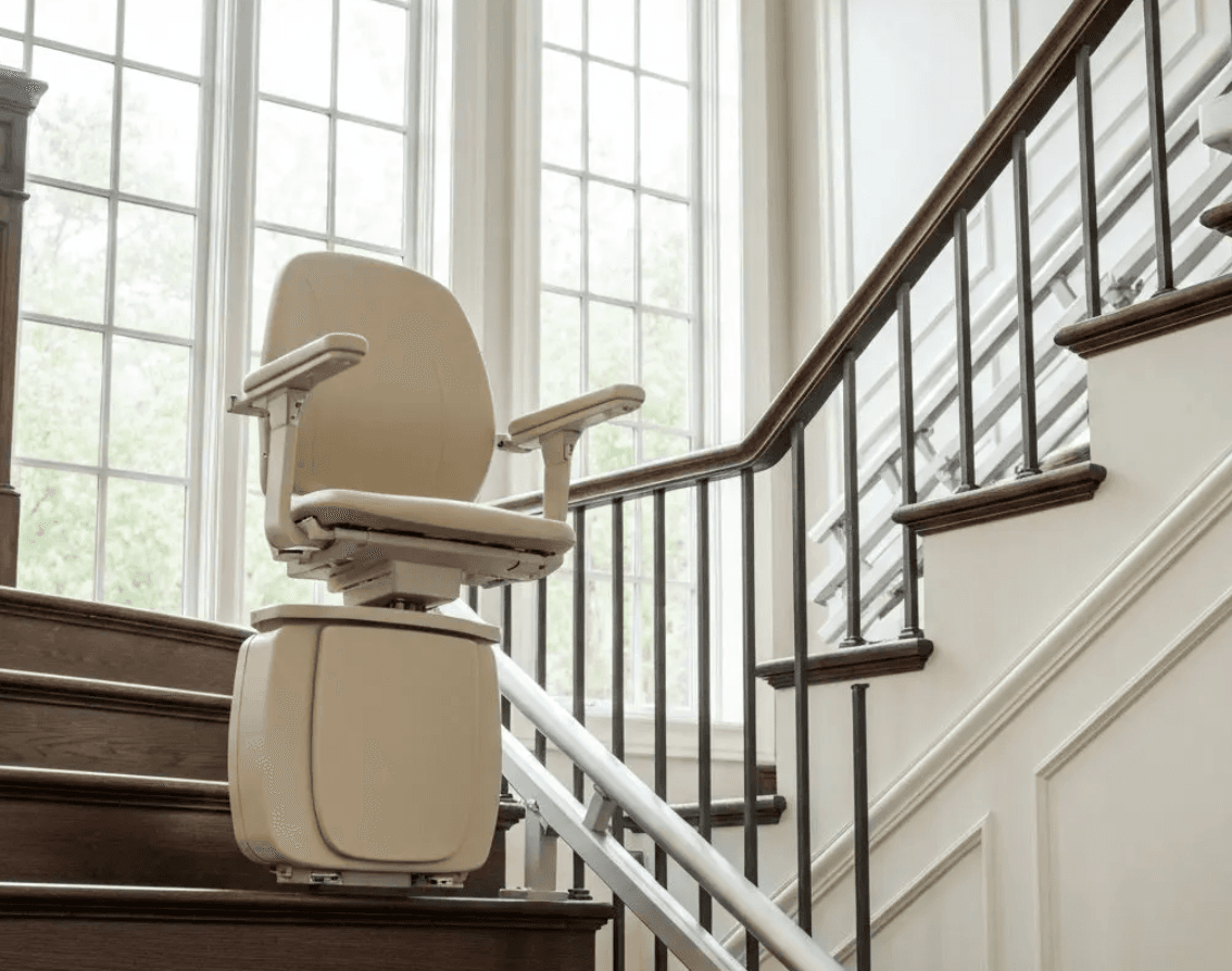 Cream stairlift on dark wooden staircase with metal railings